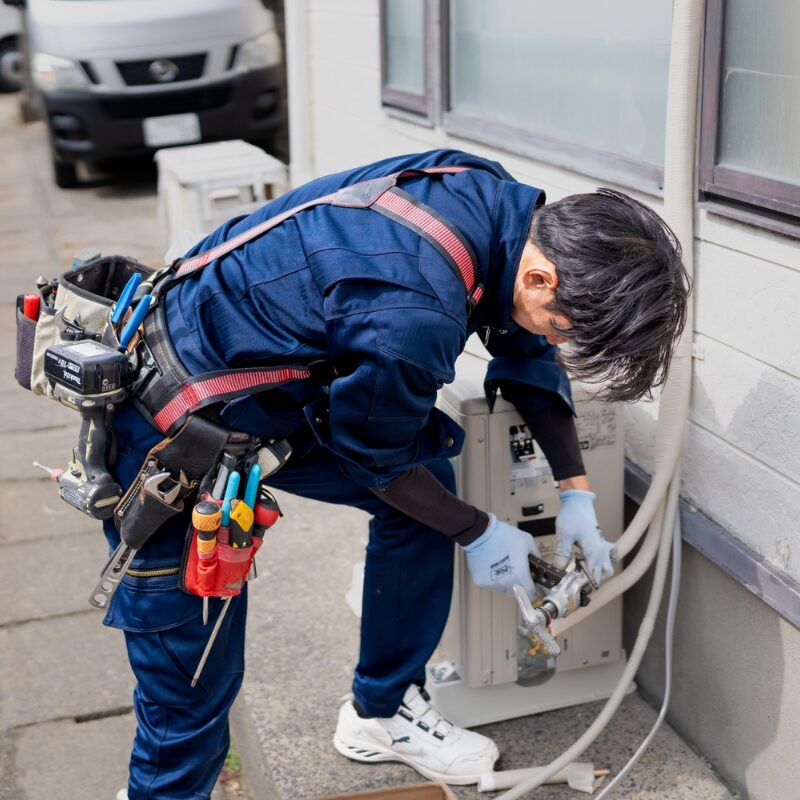 住宅の室外機まわりでエアコン工事を行う作業スタッフ